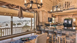A rustic kitchen with wooden cabinets, a stone backsplash, and a bar area with stools. - Rio Grande National Forest Cabin: Views & Hot Tub (Del Norte)