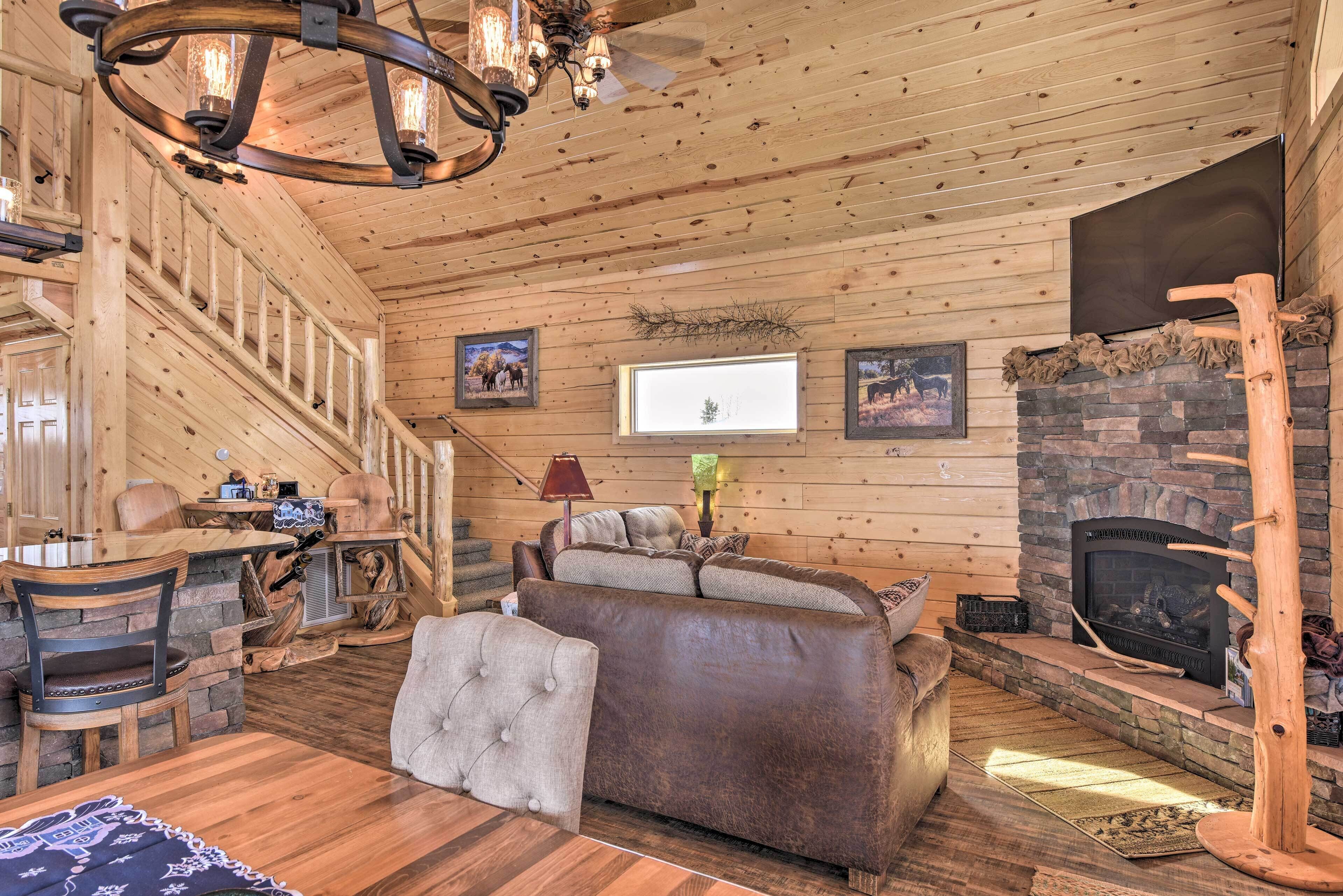 L’intérieur d’une cabane en rondins, avec une cheminée, des murs en bois, un canapé et un coin repas.