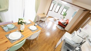 A compact living space with a dining area, kitchenette, and a small seating area with a sofa and a table. - Elle’s Shirokane guest house (Tokyo)