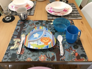 A dining table set with plates, bowls, a blue mug, and utensils on a patterned placemat. - Elle’s Shirokane guest house (Tokyo)