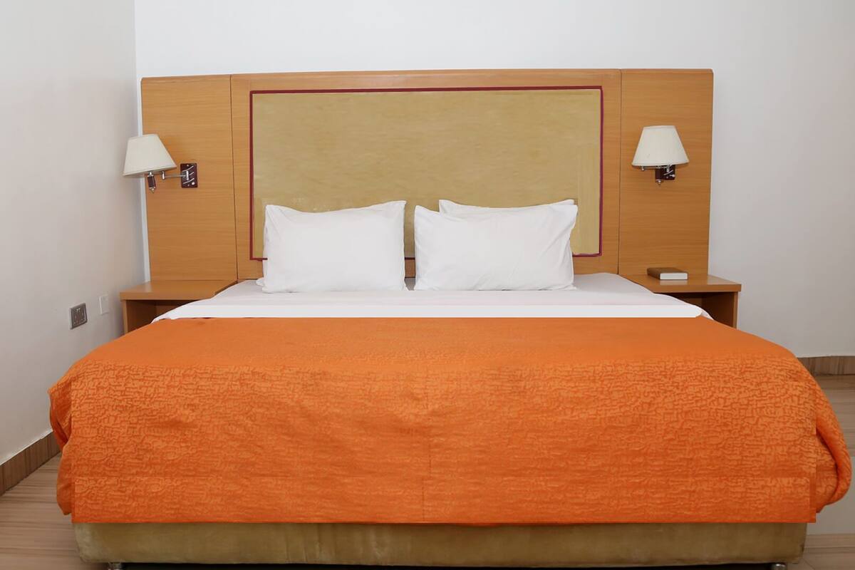 Une chambre d  ’hôtel avec un grand lit, deux lampes de chevet et une tête de lit en bois.