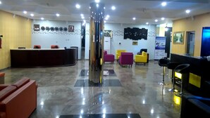 A lobby with a reception desk, multiple seating areas, and a central column. - Hotel Ibis Royale Owerri (Owerri)