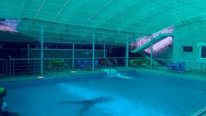 An indoor swimming pool with a diving platform, seating area, and a staircase leading to an upper level. - Hotel Ibis Royale Owerri (Owerri)