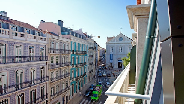 A street view with buildings, a green bus, and a pedestrian crossing.