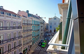 A street view with buildings, a green bus, and a pedestrian crossing.
