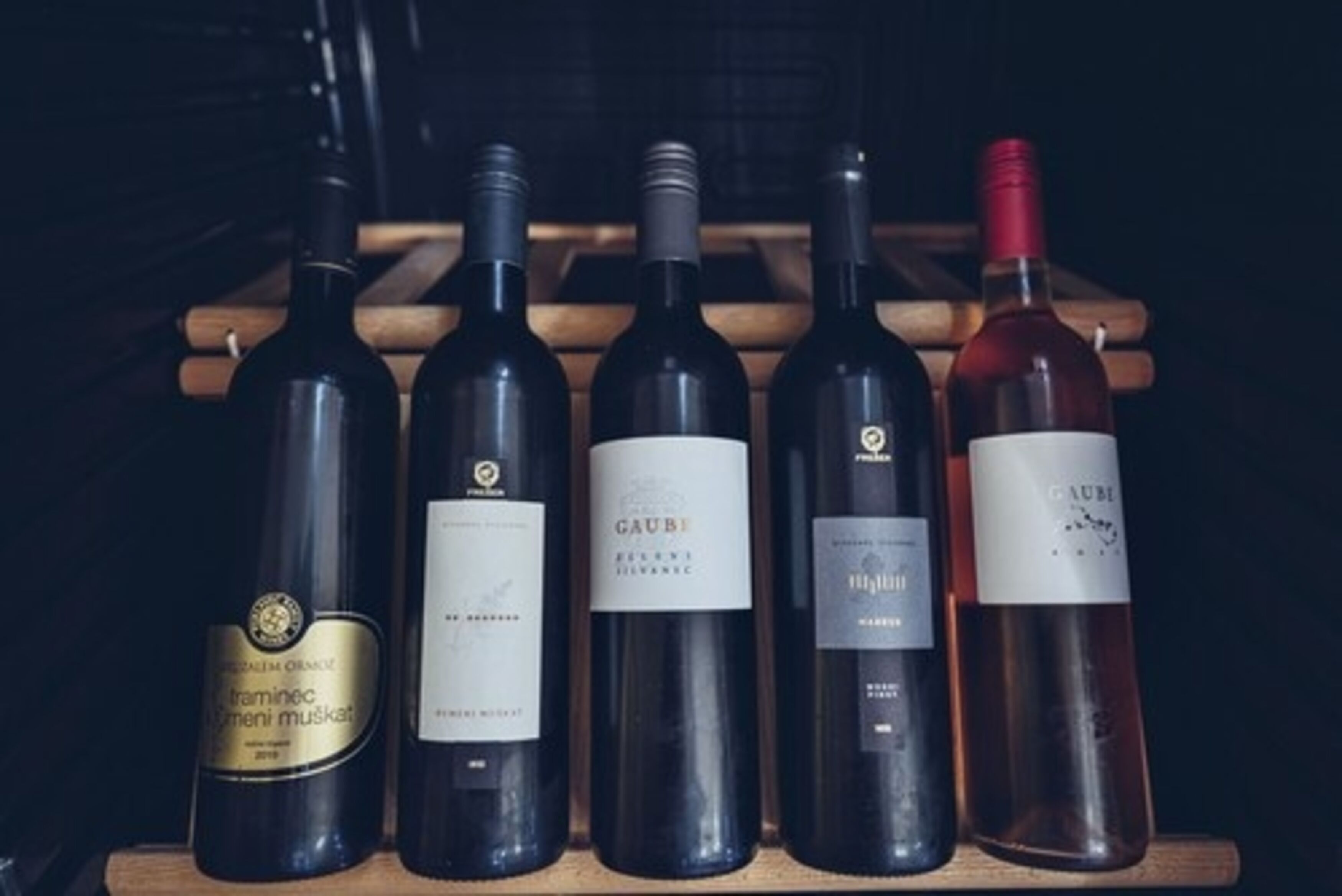A wooden wine rack holding five wine bottles.