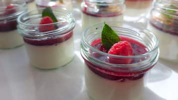 Une série de bocaux en verre contenant des desserts en couches, à base de framboises et de feuilles de menthe.