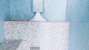 A tiled bathroom with a shower area, a sink, and a drain.
