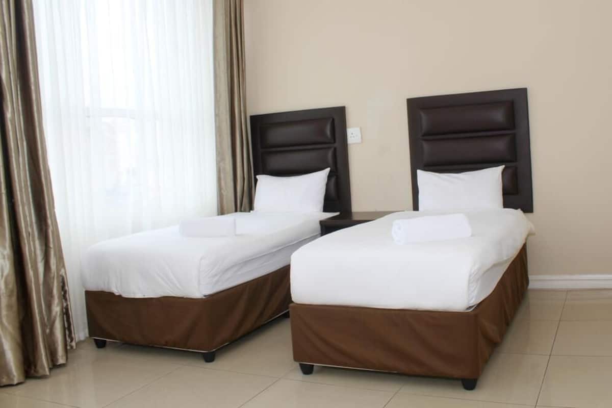 Two single beds with brown headboards and white bedding in a hotel room.
