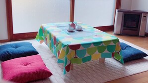 A room with a table set for tea, large windows, and an air conditioner.