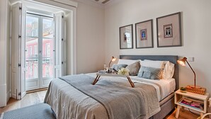 A bedroom with a bed, bedside tables, a window, and framed pictures on the wall.