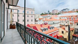 A balcony with a metal railing overlooking a cityscape with buildings of various colors and architectural styles.