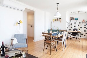 Una sala de estar moderna con comedor, suelo de madera y una pared blanca con salpicadero de baldosas blanco y negro.
