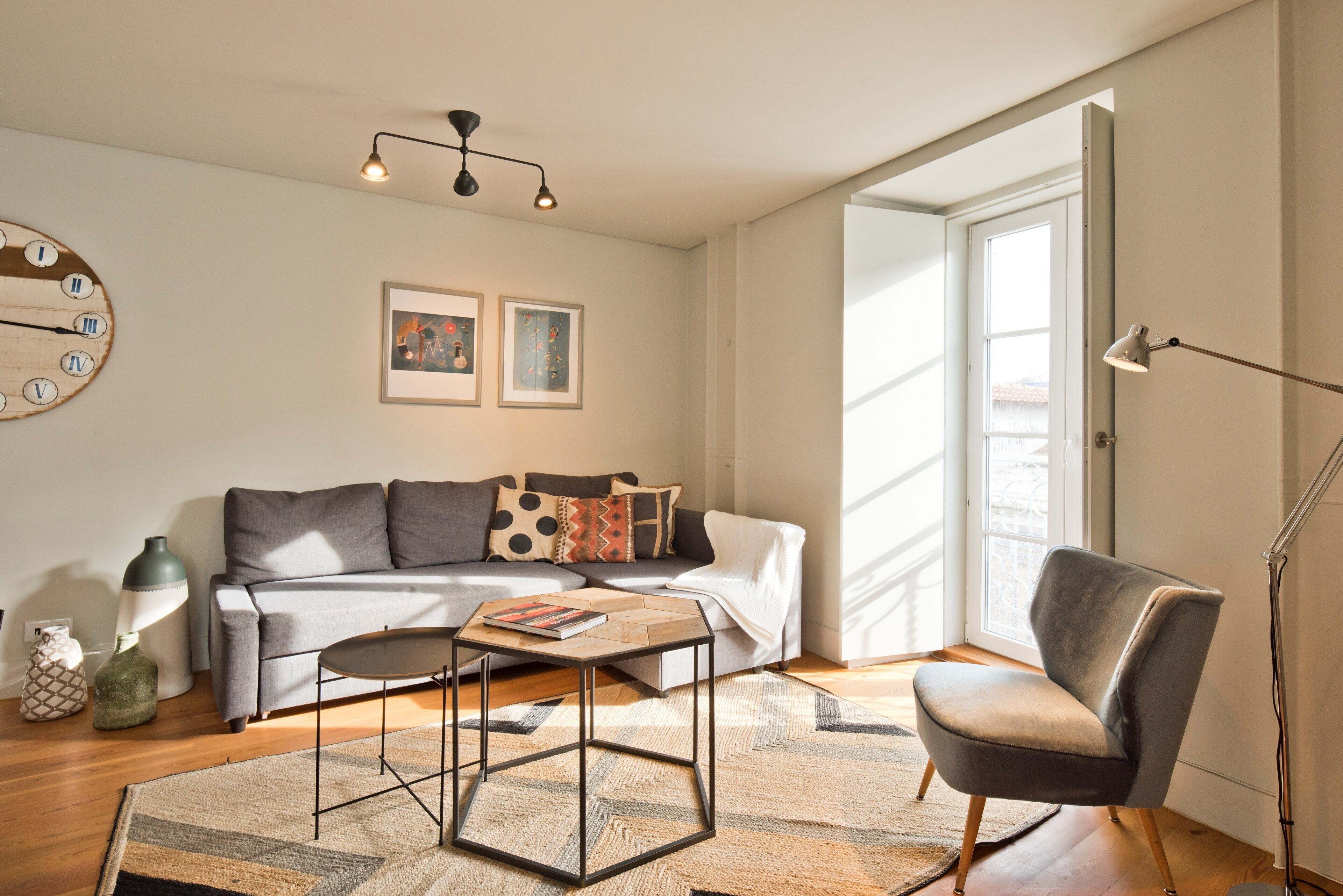 A living room with a sofa, a coffee table, a floor lamp, and a wall clock.