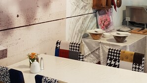 A dining area with a rustic wooden table, patterned chairs, a wall clock, and a decorative hanging light fixture. - Waldhotel und Restaurants Lemberg (Hagen)
