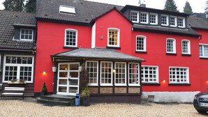 A red building with multiple windows and a covered entrance. - Waldhotel und Restaurants Lemberg (Hagen)
