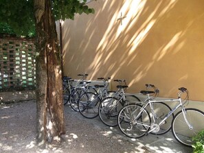Bicycles parked against a wall in a shaded area.