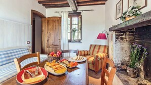 Un coin repas chaleureux avec une table en bois dressée pour le repas, un canapé à rayures et une cheminée.