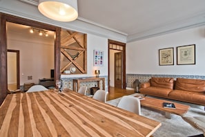 A spacious living area with a wooden dining table, a leather sofa, and a fireplace.