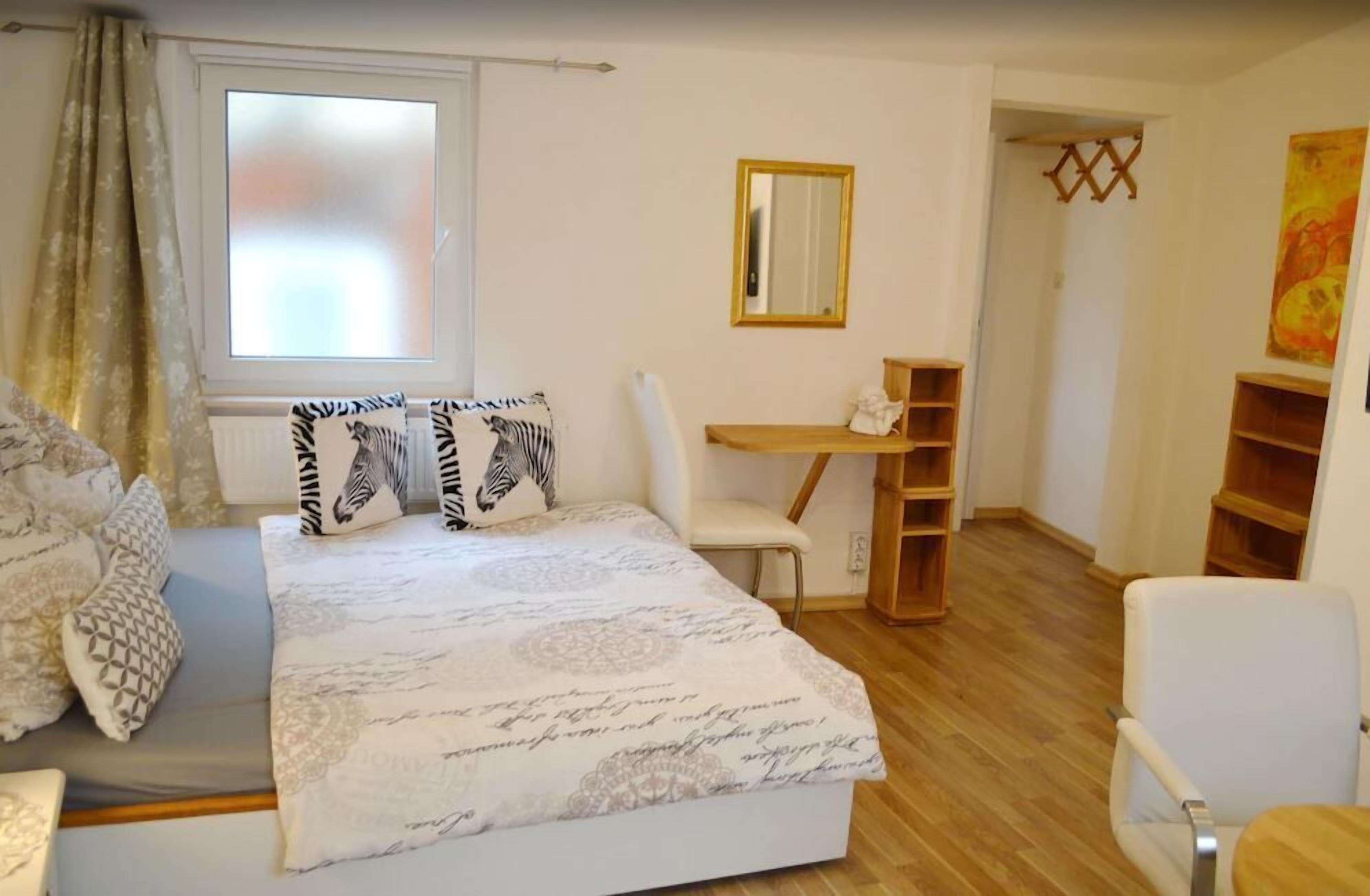 A bedroom with a bed, a desk, and a chair.