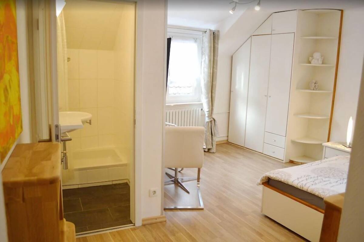 A bedroom with a bed, a wardrobe, a bathroom with a shower, and a toilet.