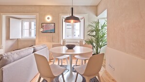A modern living room with a round dining table, a sofa, and a potted plant.