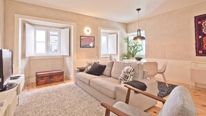 A living room with a sofa, a coffee table, a television, and a map on the wall.