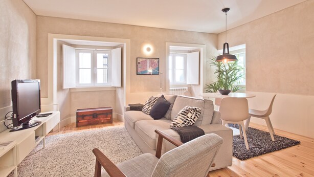 A modern living room with a sofa, armchairs, a television, and a dining area with a table and chairs.