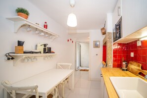 A kitchen with white cabinetry, a wooden countertop, and a red-tiled backsplash.