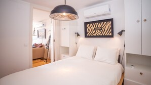 Une chambre à coucher comprenant un lit, un luminaire suspendu, une œuvre d’art à motifs zébrés, une table de chevet et une armoire.