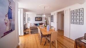 Un salon moderne avec une table à manger en bois, un canapé et un luminaire suspendu au plafond.
