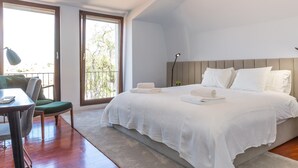A bedroom with a large bed, a desk, and a chair.