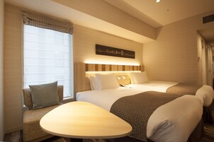 Habitación de hotel con dos camas, un ventanal con persianas, una mesita de noche y una obra de arte colgada en la pared.