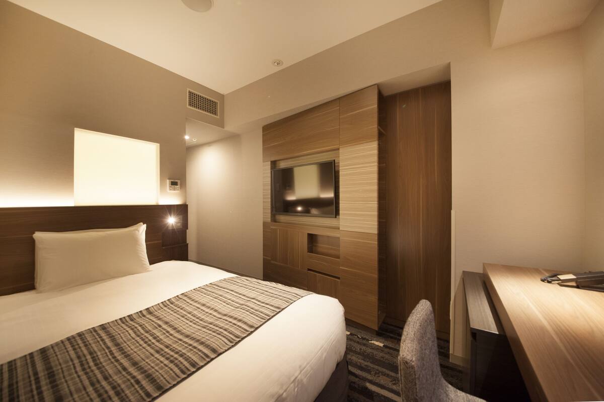 A hotel room with a large bed, a desk, and a television.