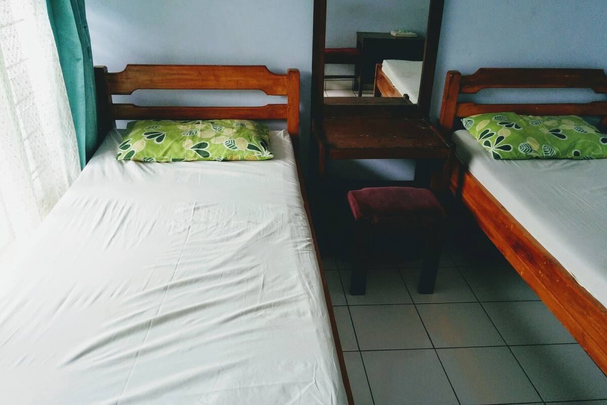 Une chambre avec deux lits simples, un bureau en bois et une chaise.