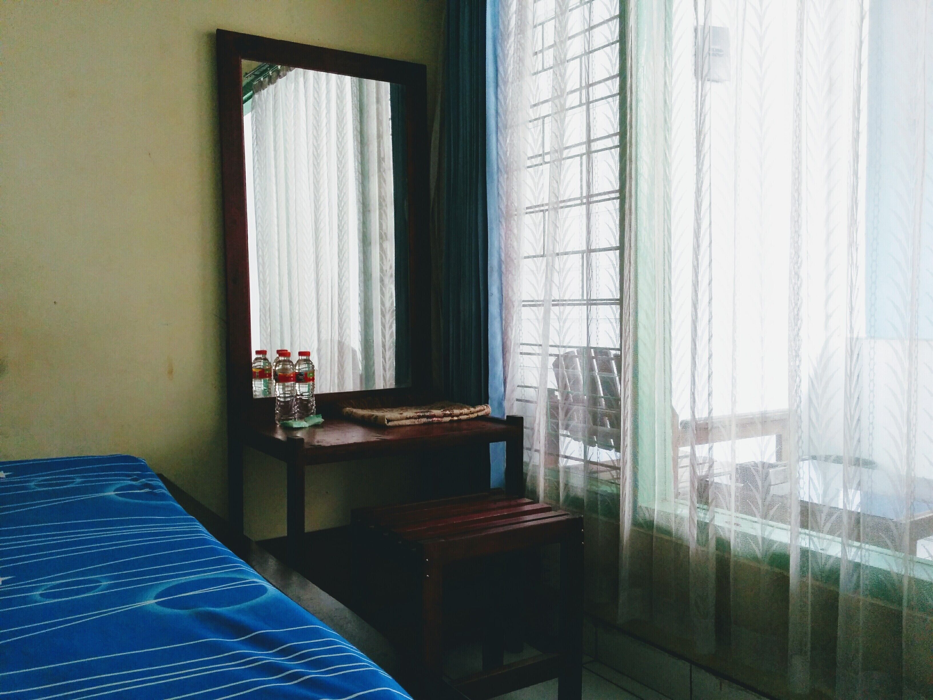 A room with a bed, a chair, a small table, and a window with curtains.