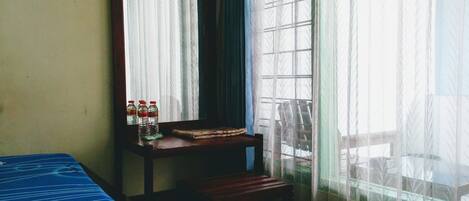 A room with a bed, a chair, a small table, and a window with curtains.