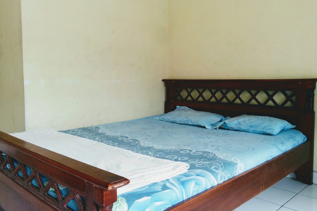 Un lit simple avec une tête de lit en bois et une couvre-lit à motifs floraux.