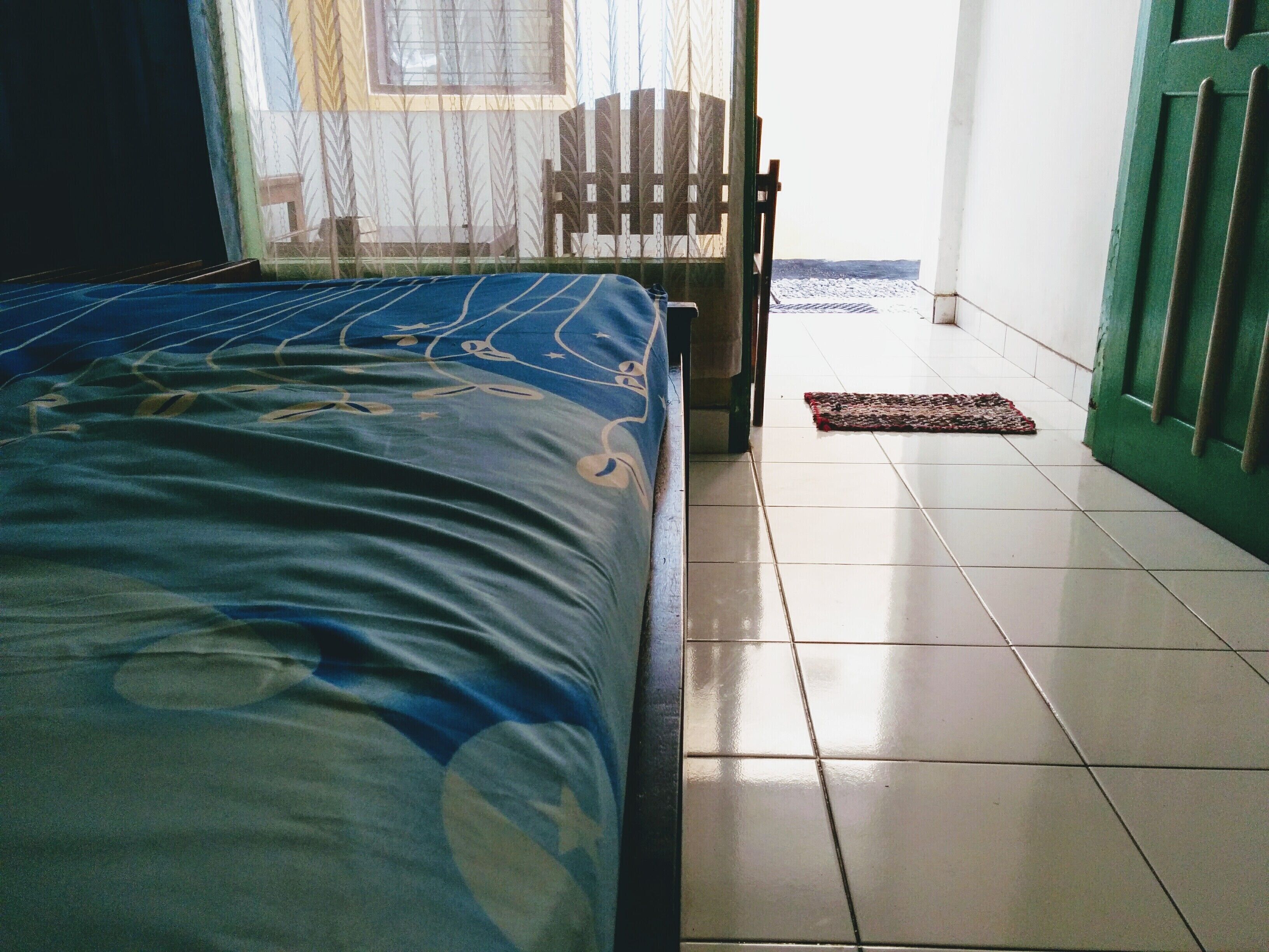 A bedroom with a bed, a chair, and a door.