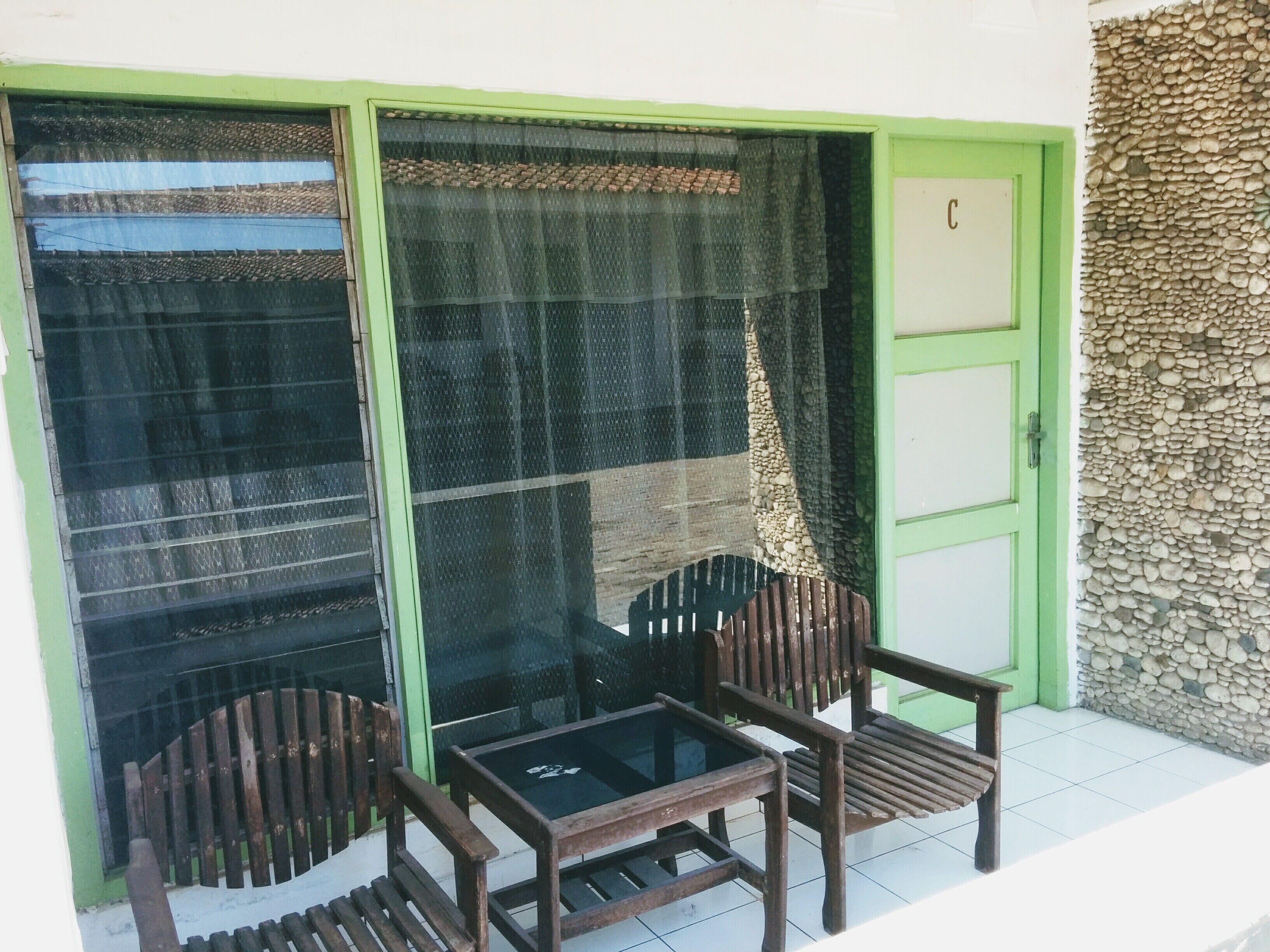A room with a sliding glass door, a small table, and two wooden chairs.