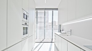 Une cuisine moderne avec des meubles blancs, une grande fenêtre et un évier en acier inoxydable.