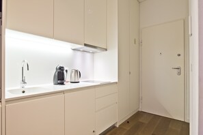 Cozinha moderna com bancada branca, pia de aço inoxidável e cafeteira.