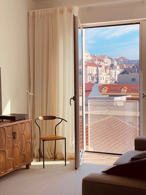 Een balkon met uitzicht op een stadsbeeld, een houten kast, een stoel en een bank.
