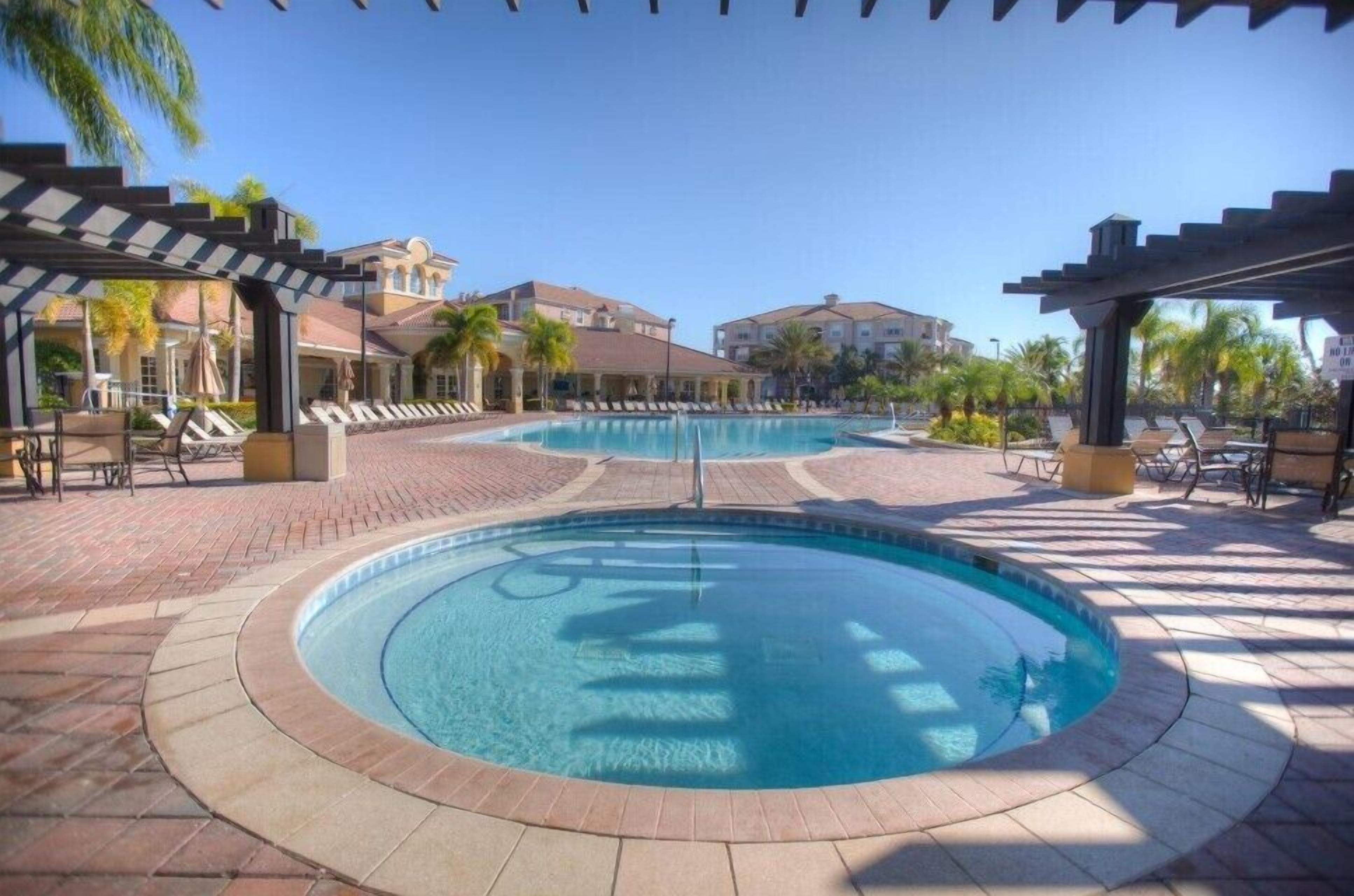 A pool area with lounge chairs and umbrellas, surrounded by buildings.