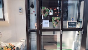 A hotel entrance with a brown door, a glass entrance, and a sign indicating a guest house. - Guest House Ringo (Otaru)