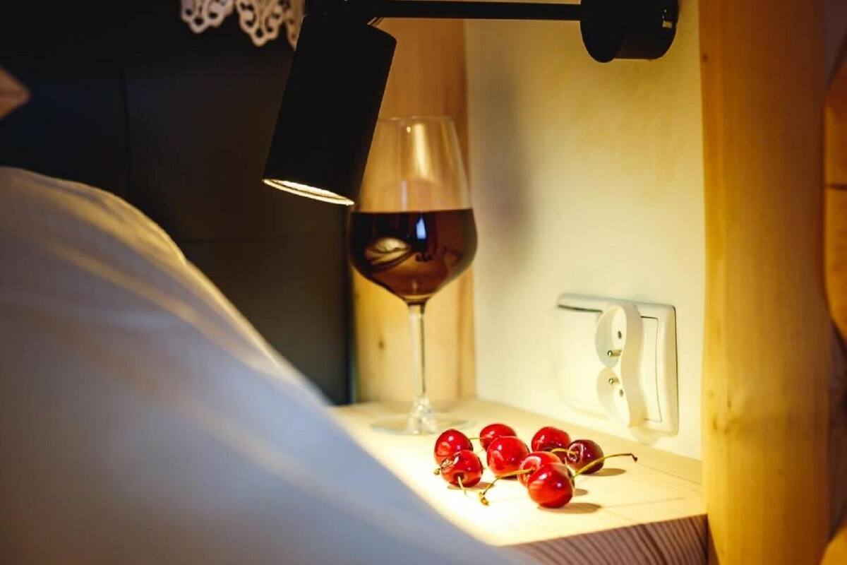 A bedside table with a wine glass and cherries.