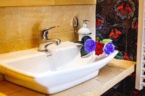Ein weißes Waschbecken mit einem modernen Wasserhahn und einer Seifenspender auf einer Holzausziehtafel.