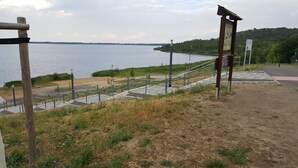 A pathway leading to a lakeside area with a wooden signpost and a metal staircase. - Vacation home (110sqm) for rent at the Geiseltalsee (Krumpa)