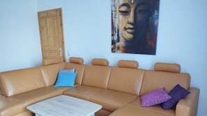 A tan leather sofa with a wooden coffee table, a blue pillow, and a purple pillow. - Vacation home (110sqm) for rent at the Geiseltalsee (Krumpa)