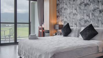 A hotel room with a large bed, a cityscape wallpaper, and a view of a sports field.